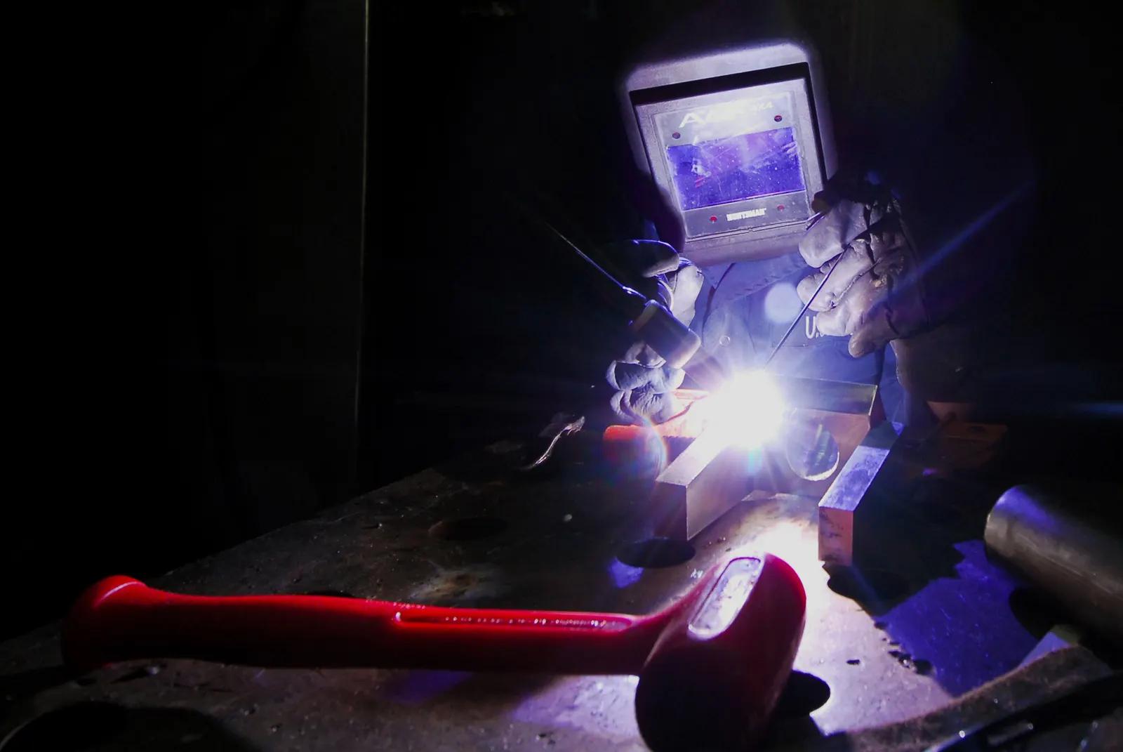 Technicien de maintenance soudant une pièce métallique dans un atelier de réparation